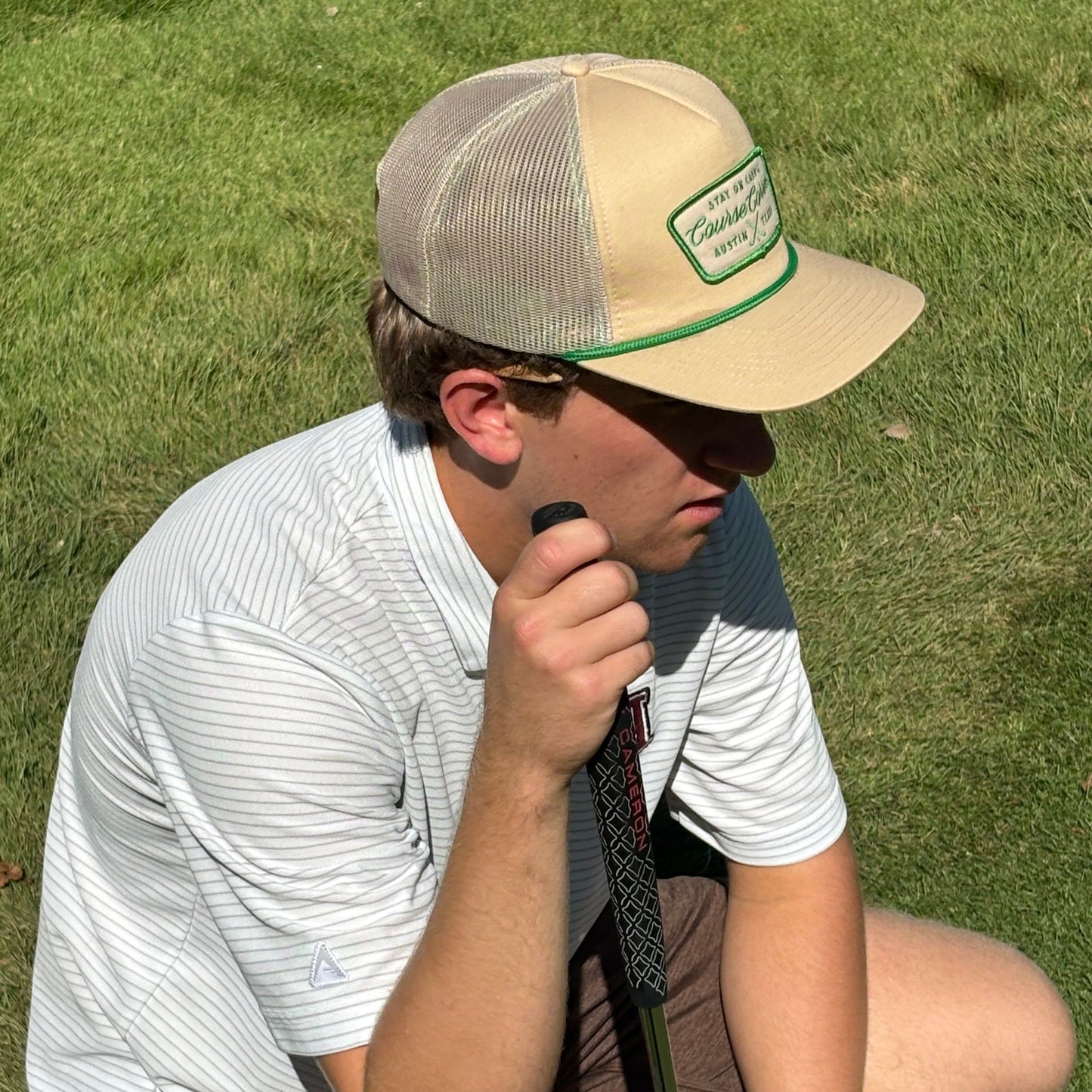 Person sitting on a golf course holding a golf club